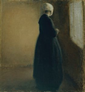 An old woman standing by a window